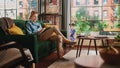 Young Handsome Adult Man Sitting on a Couch in Loft Apartment, Working from Home on Tablet Computer Royalty Free Stock Photo