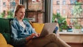 Young Handsome Adult Man Sitting on a Couch in Loft Living Room, Working from Home on Laptop Royalty Free Stock Photo