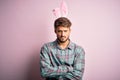 Young handsome adult man wearing cute easter rabbit ears over pink isolated background skeptic and nervous, disapproving Royalty Free Stock Photo