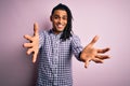 Young handsome african american afro man with dreadlocks wearing casual shirt looking at the camera smiling with open arms for hug Royalty Free Stock Photo