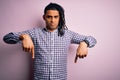 Young handsome african american afro man with dreadlocks wearing casual shirt Pointing down looking sad and upset, indicating Royalty Free Stock Photo