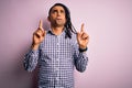 Young handsome african american afro man with dreadlocks wearing casual shirt Pointing up looking sad and upset, indicating Royalty Free Stock Photo