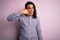 Young handsome african american afro man with dreadlocks wearing casual shirt smiling doing phone gesture with hand and fingers Royalty Free Stock Photo