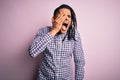 Young handsome african american afro man with dreadlocks wearing casual shirt Yawning tired covering half face, eye and mouth with Royalty Free Stock Photo