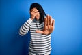 Young handsome african american afro man with dreadlocks wearing casual striped sweater covering eyes with hands and doing stop Royalty Free Stock Photo