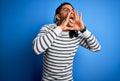 Young handsome african american afro man with dreadlocks wearing casual striped sweater Shouting angry out loud with hands over Royalty Free Stock Photo