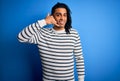 Young handsome african american afro man with dreadlocks wearing casual striped sweater smiling doing phone gesture with hand and Royalty Free Stock Photo