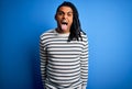 Young handsome african american afro man with dreadlocks wearing casual striped sweater sticking tongue out happy with funny Royalty Free Stock Photo