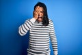 Young handsome african american afro man with dreadlocks wearing casual striped sweater Yawning tired covering half face, eye and Royalty Free Stock Photo