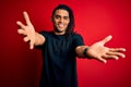 Young handsome african american afro man with dreadlocks wearing casual t-shirt looking at the camera smiling with open arms for Royalty Free Stock Photo