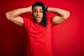 Young handsome african american afro man with dreadlocks wearing red casual t-shirt Crazy and scared with hands on head, afraid Royalty Free Stock Photo