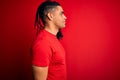 Young handsome african american afro man with dreadlocks wearing red casual t-shirt looking to side, relax profile pose with Royalty Free Stock Photo