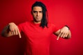 Young handsome african american afro man with dreadlocks wearing red casual t-shirt Pointing down looking sad and upset, Royalty Free Stock Photo