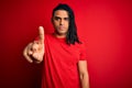 Young handsome african american afro man with dreadlocks wearing red casual t-shirt Pointing with finger up and angry expression, Royalty Free Stock Photo