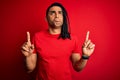 Young handsome african american afro man with dreadlocks wearing red casual t-shirt Pointing up looking sad and upset, indicating Royalty Free Stock Photo