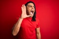 Young handsome african american afro man with dreadlocks wearing red casual t-shirt shouting and screaming loud to side with hand Royalty Free Stock Photo