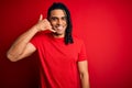 Young handsome african american afro man with dreadlocks wearing red casual t-shirt smiling doing phone gesture with hand and Royalty Free Stock Photo