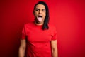 Young handsome african american afro man with dreadlocks wearing red casual t-shirt sticking tongue out happy with funny Royalty Free Stock Photo