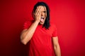 Young handsome african american afro man with dreadlocks wearing red casual t-shirt Yawning tired covering half face, eye and Royalty Free Stock Photo