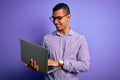 Young handsome african american business man working using laptop over purple background with a happy face standing and smiling Royalty Free Stock Photo