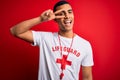 Young handsome african american lifeguard man wearing t-shirt with red cross and whistle Doing peace symbol with fingers over