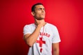 Young handsome african american lifeguard man wearing t-shirt with red cross and whistle Touching painful neck, sore throat for
