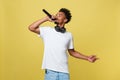 Young handsome African American Male Singer Performing with Microphone. Isolated over yellow gold background. Royalty Free Stock Photo