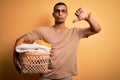 Young handsome african american man doing housework holding wicker basket with clothes with angry face, negative sign showing