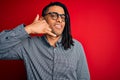 Young handsome african american man with dreadlocks wearing casual shirt and glasses smiling doing phone gesture with hand and Royalty Free Stock Photo