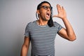 Young handsome african american man with dreadlocks wearing striped t-shirt and glasses shouting and screaming loud to side with Royalty Free Stock Photo