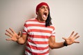 Young handsome african american man with dreadlocks wearing striped t-shirt and wool hat crazy and mad shouting and yelling with Royalty Free Stock Photo