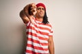 Young handsome african american man with dreadlocks wearing striped t-shirt and wool hat looking unhappy and angry showing Royalty Free Stock Photo