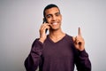 Young handsome african american man having conversation talking on the smartphone surprised with an idea or question pointing Royalty Free Stock Photo