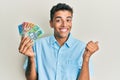 Young handsome african american man holding australian dollars screaming proud, celebrating victory and success very excited with Royalty Free Stock Photo