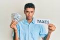 Young handsome african american man holding dollars and taxes paper skeptic and nervous, frowning upset because of problem