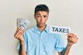 Young handsome african american man holding dollars and taxes paper skeptic and nervous, frowning upset because of problem