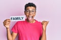 Young handsome african american man holding family paper pointing thumb up to the side smiling happy with open mouth Royalty Free Stock Photo