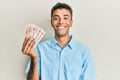 Young handsome african american man holding 10 united kingdom pounds banknotes looking positive and happy standing and smiling