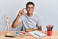 Young handsome african american man painter sitting palette and art manikin smiling and confident gesturing with hand doing small Royalty Free Stock Photo