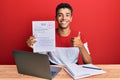 Young handsome african american man showing a passed exam smiling happy and positive, thumb up doing excellent and approval sign Royalty Free Stock Photo