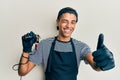 Young handsome african american man tattoo artist wearing professional uniform and gloves holding tattooer machine approving doing Royalty Free Stock Photo