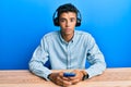 Young handsome african american man using smartphone wearing headphones relaxed with serious expression on face Royalty Free Stock Photo