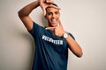 Young handsome african american man volunteering wearing t-shirt with volunteer message smiling making frame with hands and