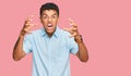 Young handsome african american man wearing casual clothes shouting frustrated with rage, hands trying to strangle, yelling mad Royalty Free Stock Photo