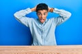 Young handsome african american man wearing casual clothes sitting on the table crazy and scared with hands on head, afraid and Royalty Free Stock Photo