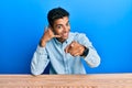 Young handsome african american man wearing casual clothes sitting on the table smiling doing talking on the telephone gesture and Royalty Free Stock Photo