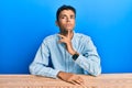 Young handsome african american man wearing casual clothes sitting on the table thinking concentrated about doubt with finger on Royalty Free Stock Photo