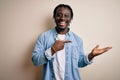 Young handsome african american man wearing casual denim shirt over white background amazed and smiling to the camera while Royalty Free Stock Photo