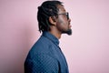 Young handsome african american man wearing casual shirt and glasses over pink background looking to side, relax profile pose with Royalty Free Stock Photo