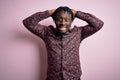 Young handsome african american man wearing casual shirt standing over pink background Crazy and scared with hands on head, afraid Royalty Free Stock Photo